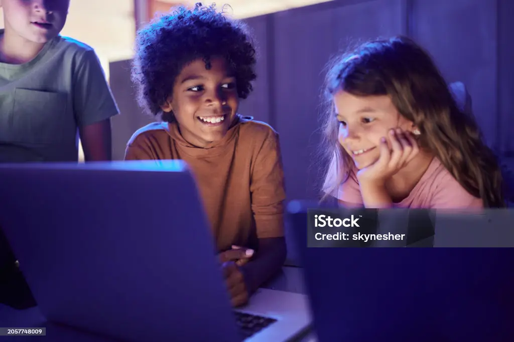 Children smiling together while using laptops